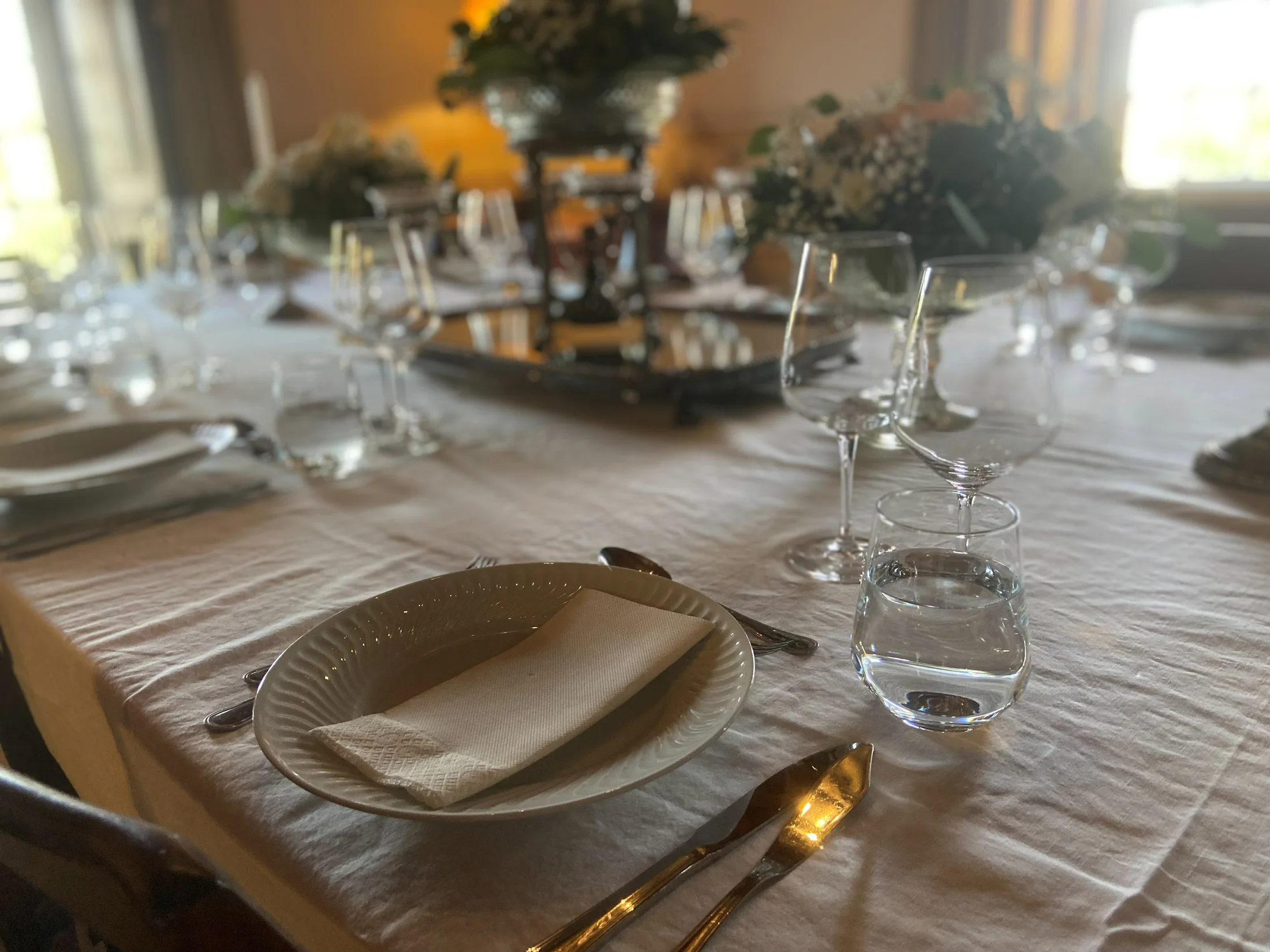 Mesa de jantar preparada com loiça, copos e flores